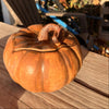 Ceramic pumpkin on a wooden surface with blurred background