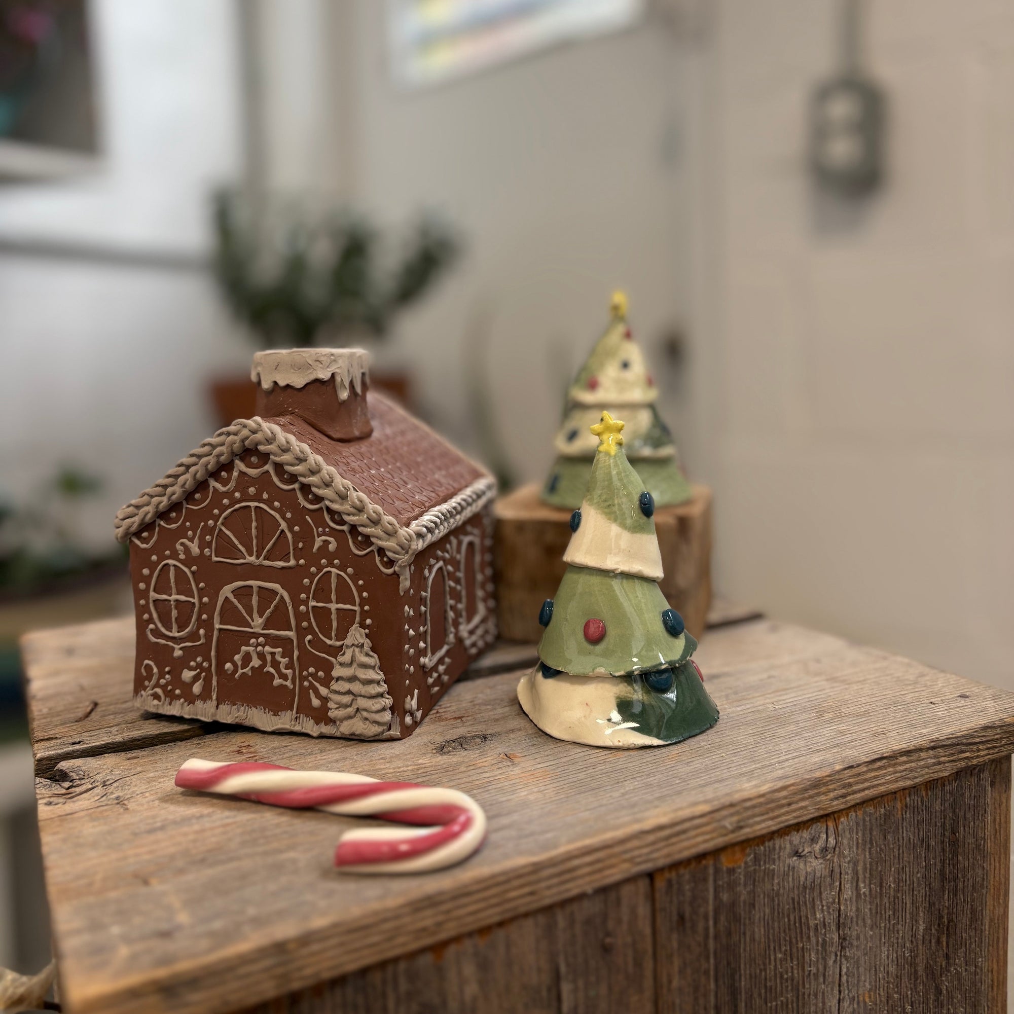 Decorative gingerbread house and tree on a wooden surface with a blurred indoor background