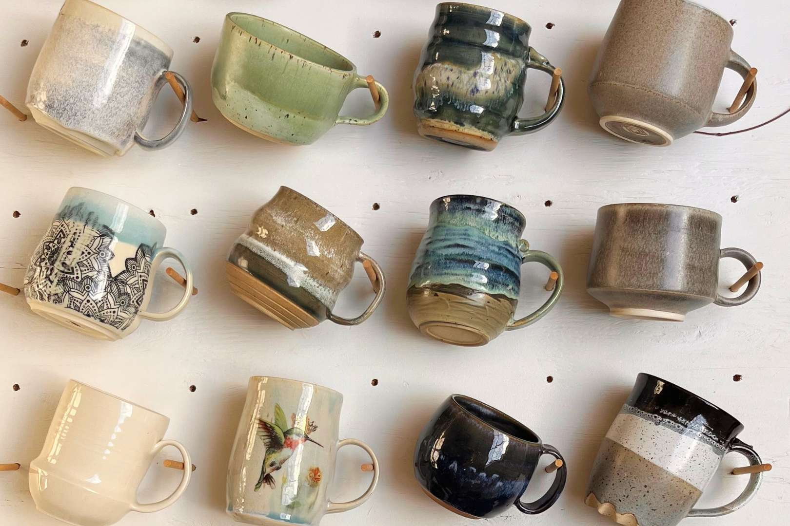 Collection of various ceramic mugs on a white wall with black dots
